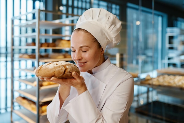 young female baker smelling appetizing fresh bread modern commercial bakery house background baked products production 266732 32699